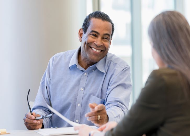 Smiling man speaking with woman across desk